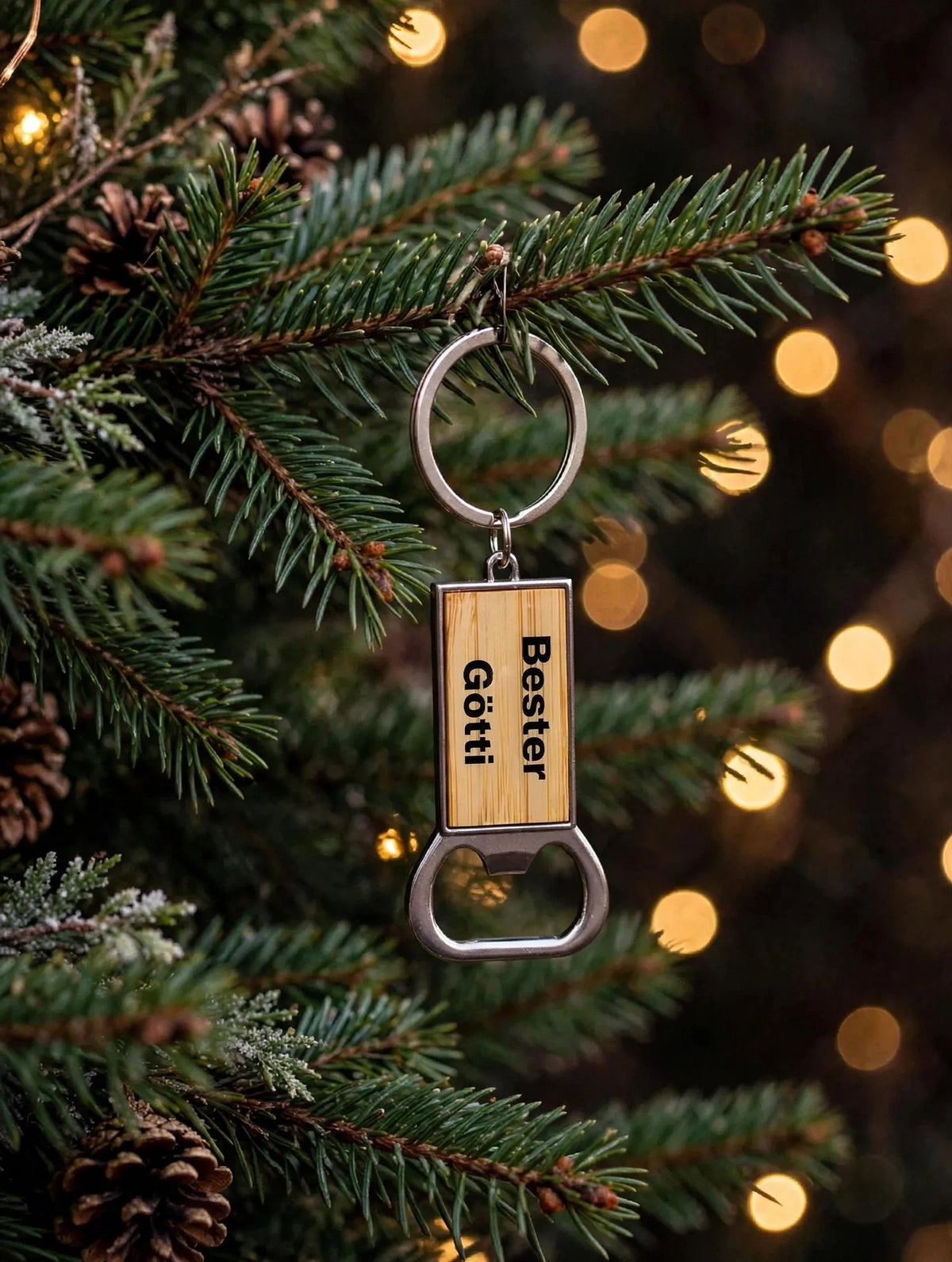 Bambus Schlüsselanhänger Bester Götti mit Vinylfolie und Epoxie als Christbaumschmuck an Tannenzweig mit Lichterkette