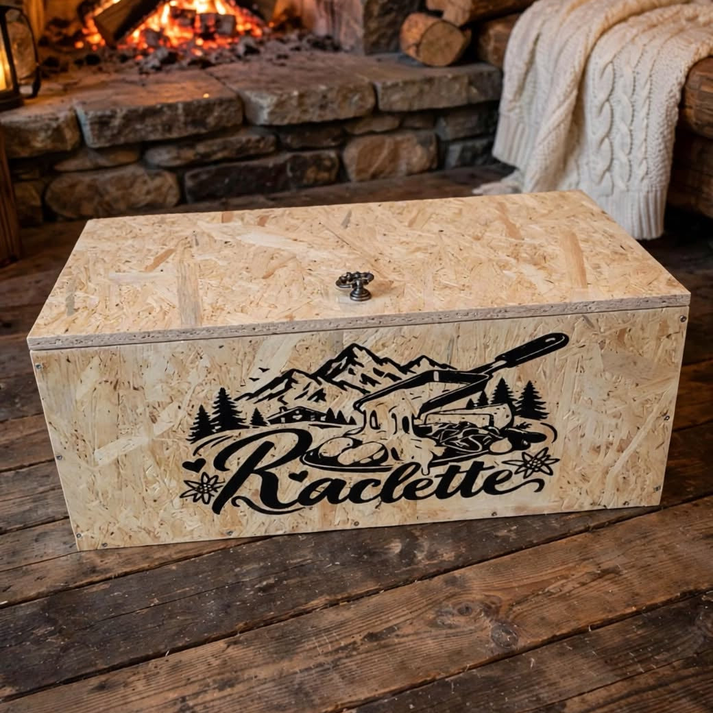 Raclette Ofen Kiste nach Mass handgemacht OSB Holz mit Raclette Logo Berge Tannen Pfännchen, geschlossene Box mit Kugelschnäpper auf Holzboden im Chalet mit Kaminfeuer, handgemacht in Hämikon bei Hitzkirch