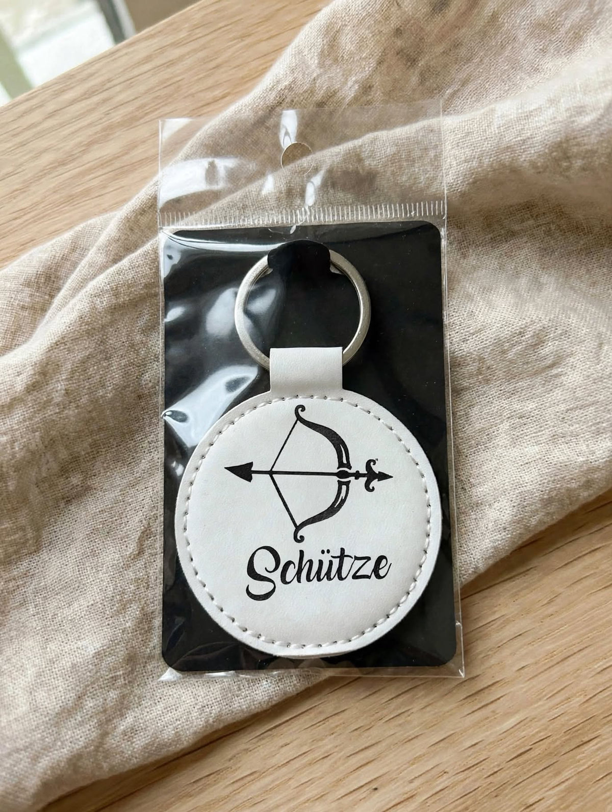 Schlüsselanhänger Schütze Weiss verpackt auf schwarzem Karton in Klarsicht-Hülle, Geschenkverpackung