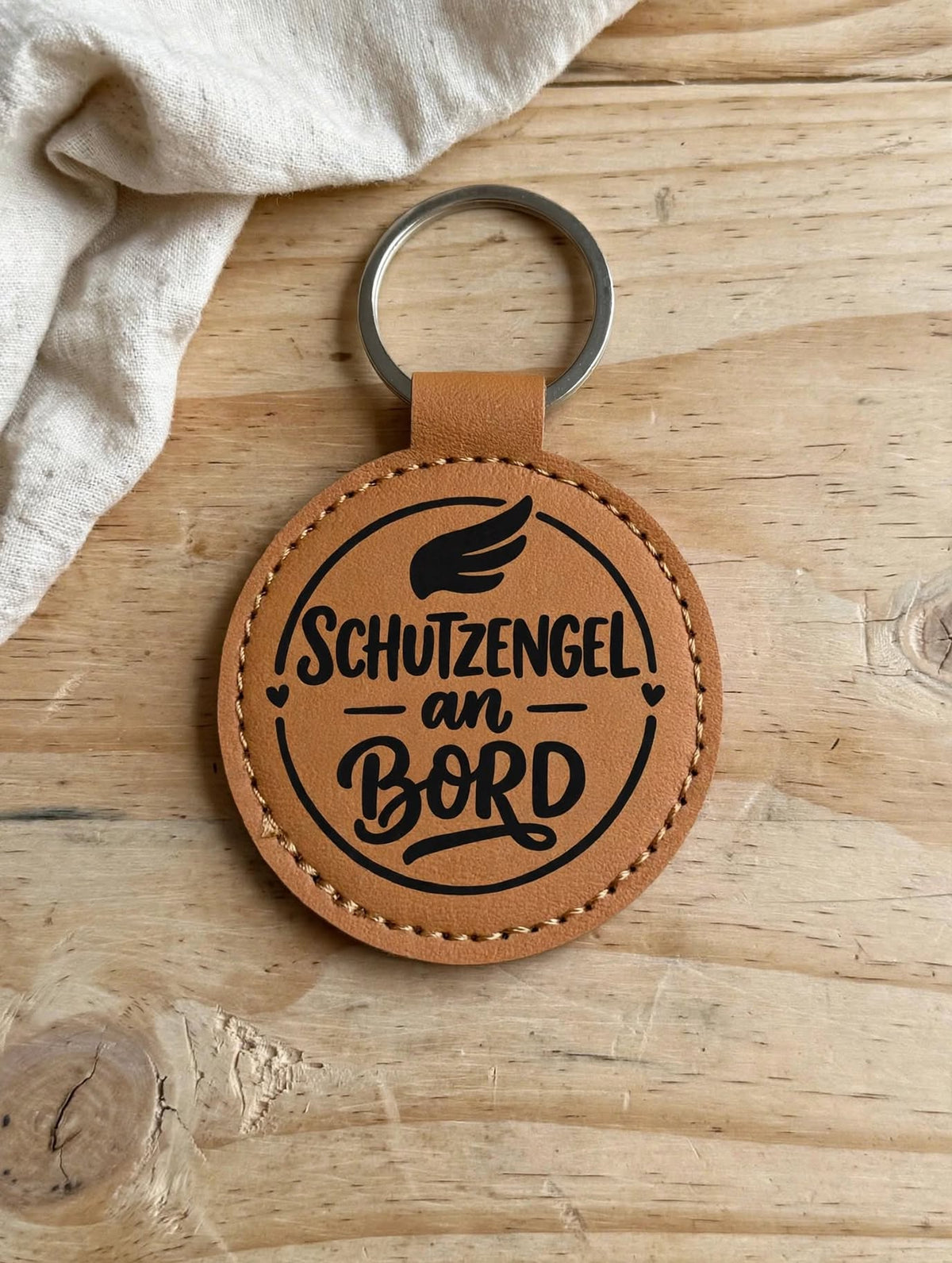 Schlüsselanhänger Schutzengel an Bord dunkelbraun - runder Kunstleder Anhänger mit schwarzem Spruch auf Holztisch - Geschenk Schutzengel Glücksbringer für Autofahrer
