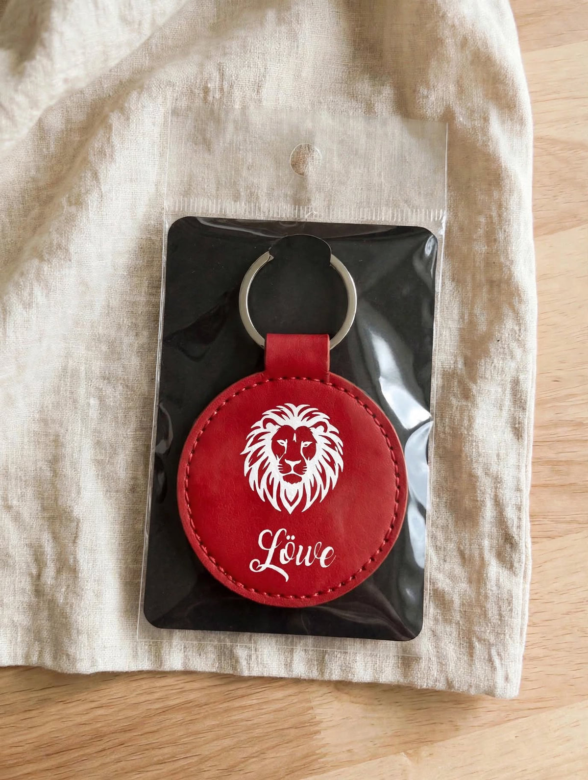Schlüsselanhänger Sternzeichen Löwe rot in Verpackung – runder Kunstleder Anhänger mit weissem Löwen Motiv und Schriftzug Löwe als Geschenk verpackt